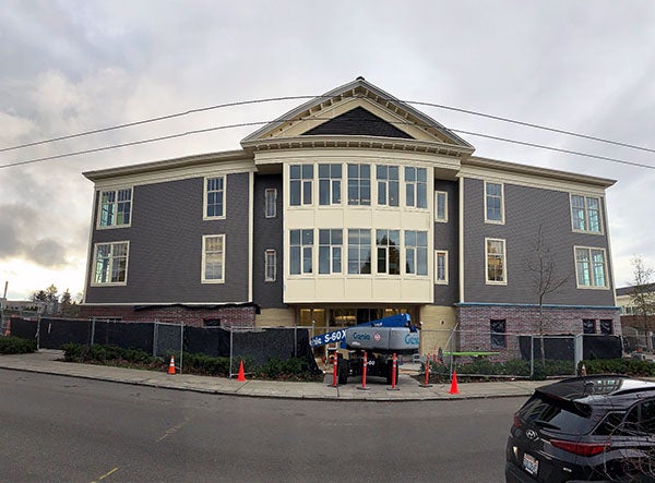 a three story building with a lighter center area bumped out with a peaked roof