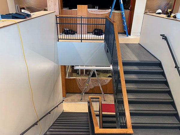a stairway with stairs going up and stairs going down. the railings are metal with wood tops