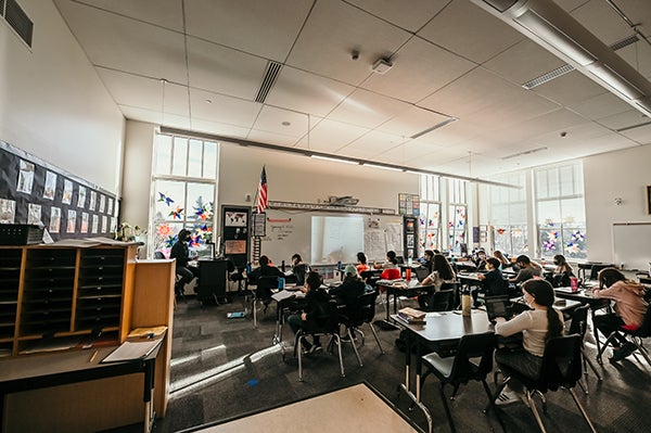 a classroom with a teacher and students sitting at tables