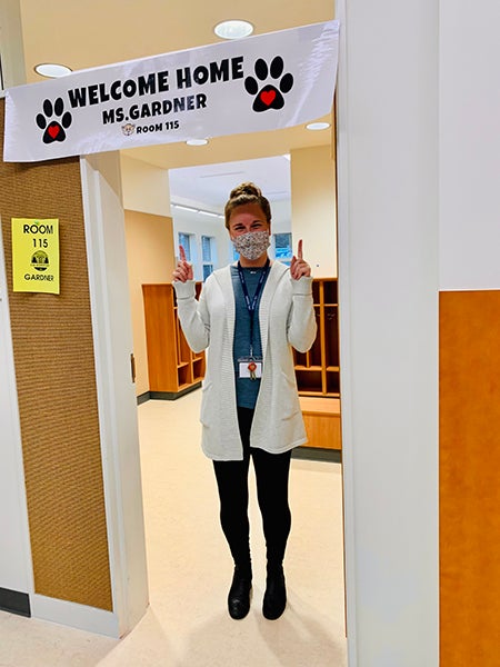 a person standing in a doorway pointing to a sign that says welcome home