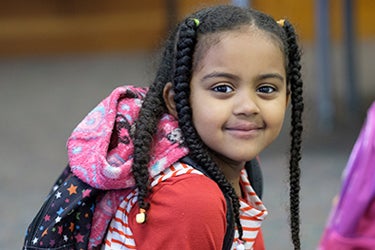 A young student smiles for a photo in a classroom