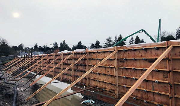 construction site with tall wooden frames for concrete with a pumper truck behind it