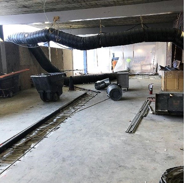 a trench with rebar is seen in the middle of a concrete floor with construction materials around it