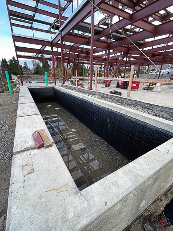 a concrete frame lined with black with a steel framework in the background