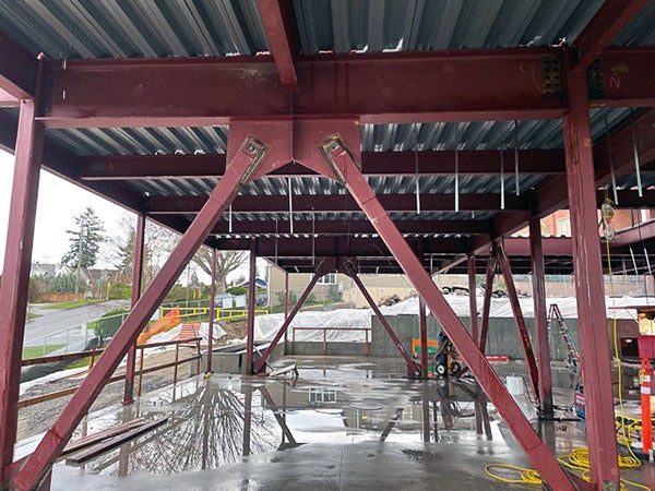 a steel frame has braces and metal decking above a concrete floor