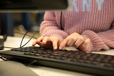 a child's hands are shown typing on a computer keyboard