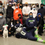 Students, Seahawk cheerleaders and mascot pose for a photo in a Target store.