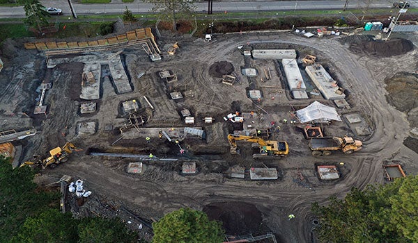 aerial view of construction with equipment digging and concrete rectangles