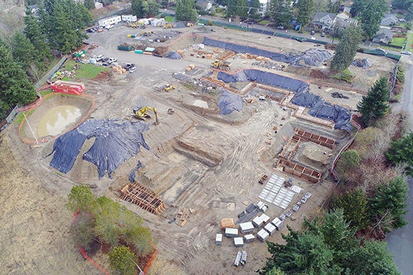 aerial view of a large construction jobsite with piles of earth, wood frames, and construction equipment
