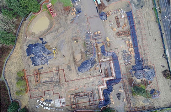 aerial view of a large construction project with the outline of the future building on top