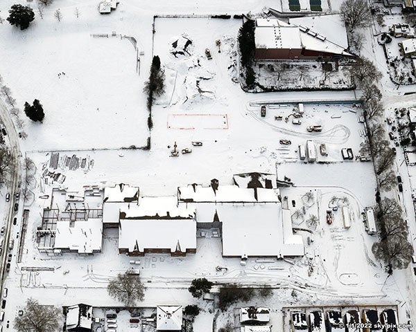 snow on a large building with part of it under construction