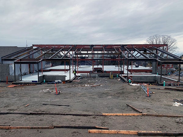 a steel framed building under construction is attached to an existing building at one end