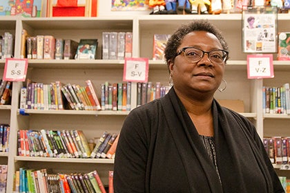 Trinia Washington poses for a photo in a library in front of many books.
