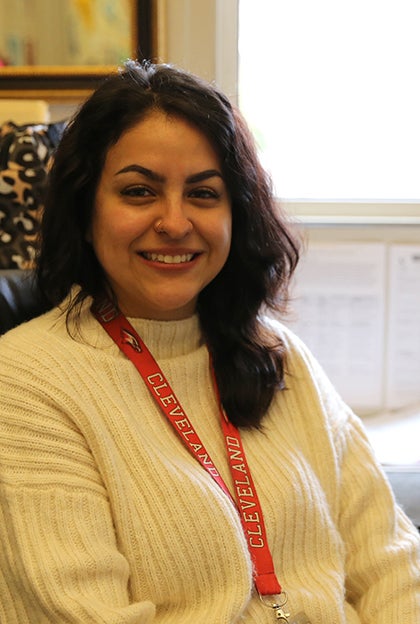 A woman sits on a chair and smiles for a photo