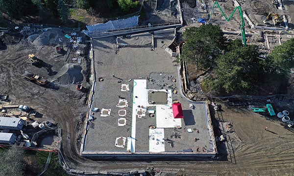 aerial view of a construction site with the shape of the building outlined in concrete and building pad preparations between them