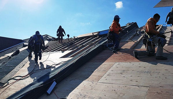 workers installing a roof under a blue sky
