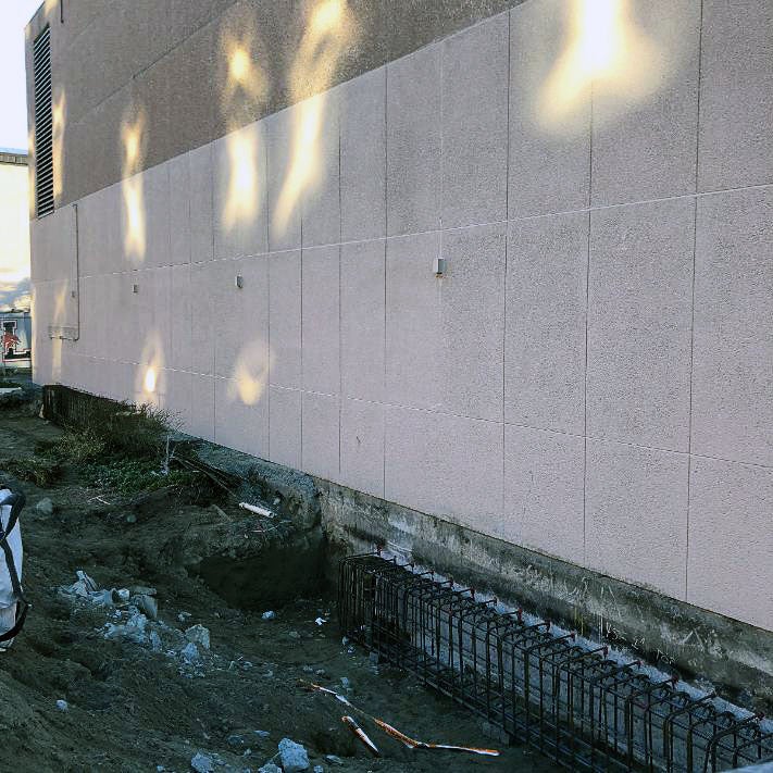 an existing wall with a trench below it that has seismic supports installed