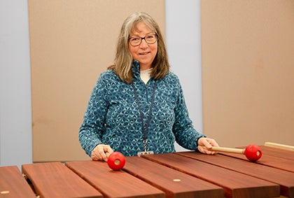 Katie Lenoue smiles for a photo while standing at a playing a marimba.