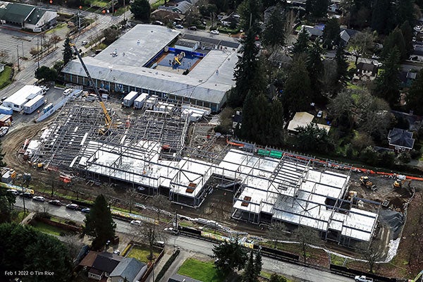aerial view of a building under constructon with steel framing and a large building in the background