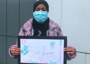 A student holds a sign that says welcome in Somali