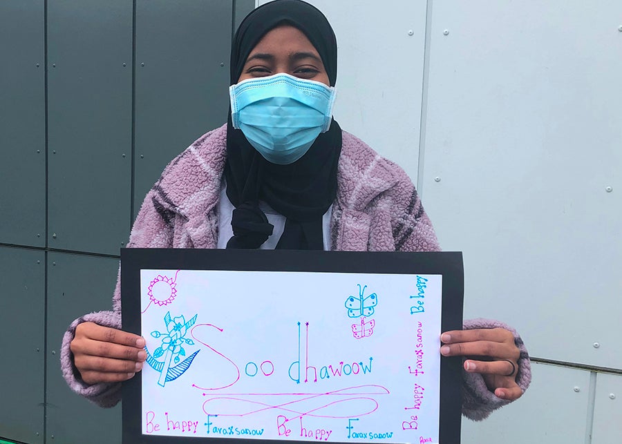 A student holds a sign that says welcome in Somali