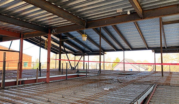 a room under construction with a metal roof and metal floor that has rebar across it
