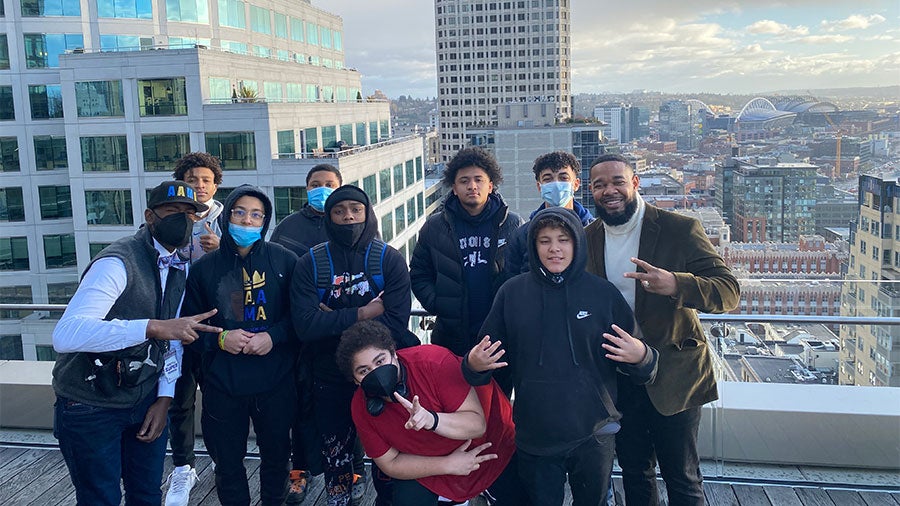 A group of students and adults pose for a photo on top of a building in downtown Seattle.