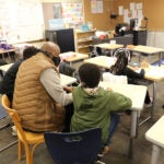 A teacher and students sit together in a classroom talking