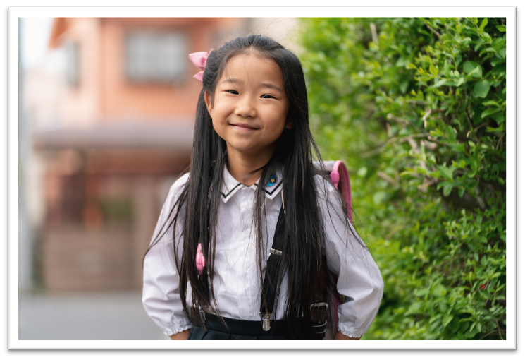 A young student stands in front of a building