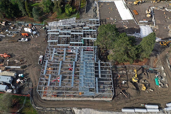 aerial view of structural steel framing being installed on a concrete pad for a large buidling
