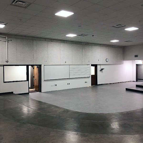 a large room with white boards on one wall and partial carpet in a curved space