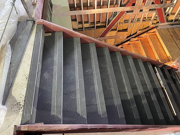 a concrete stairway on one level with a wood stairway on the next level down