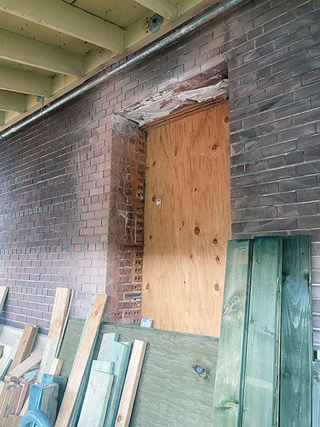 a concrete wall has a space for a window with plywood instead of glass