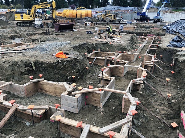 wooden formwork is in place in holes in the dirt of a construction site