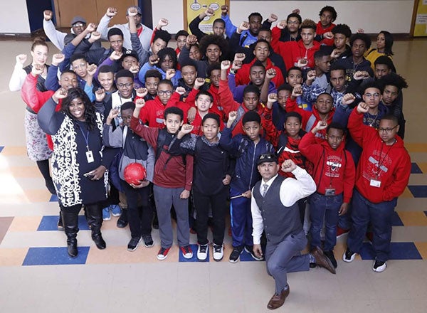 A group photo that includes Mia Williams and many students and educators with their right fist in the air