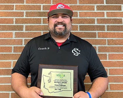 A man stands holding an award