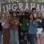 A large group of students pose for a photo in front of a hand painted sign that says Ingraham
