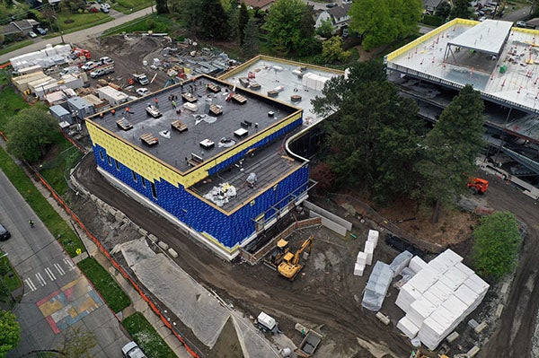 Part of a building under construction with blue and yellow material on the exterior