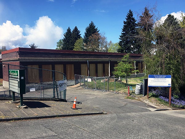 a driveway between chain link fences with a boarded up brick building