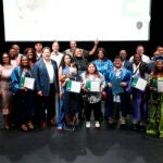 A large group gathers on a stage to pose for a photo at a graduation ceremony