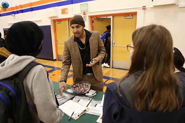 Local entrepreneur talks with students at a booth during Rainier Beach High School’s Black Excellence Fair.