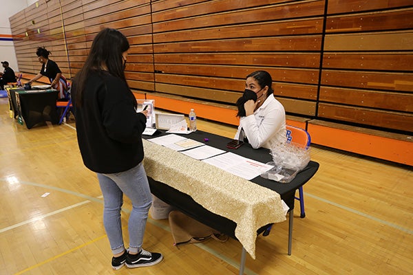 Student at the Black Excellence Fair talks with a doctor inside the Rainier Beach gym.