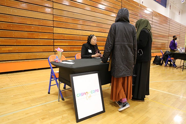 Students at Rainier Beach High School's Black Excellence Fair meet with the owner of a Cream Cone in the school’s gym.