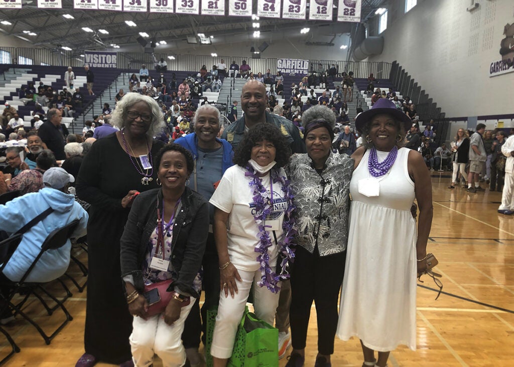A group of alumni stand together in the Garfield gym