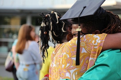 A graduate hugs a family member at a graduation ceremony