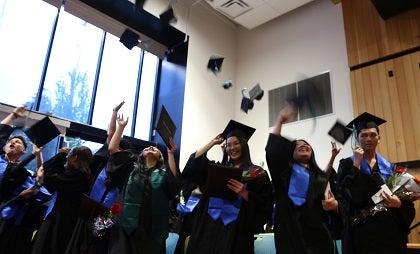 A group of graduates throw their caps in the air 