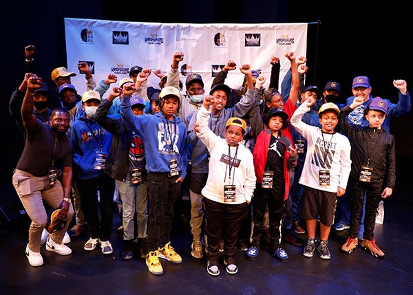 A group of students and mentors gather for a photo on a stage.