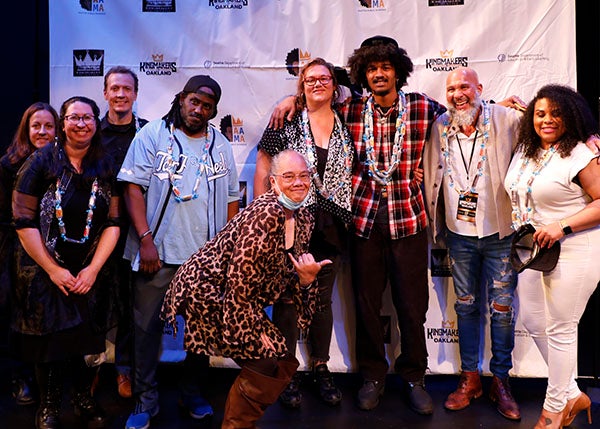 A group of students and mentors gather for a photo on a stage.