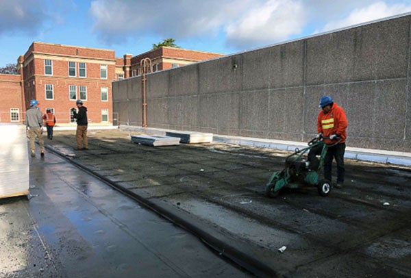 people working with machines on a roof