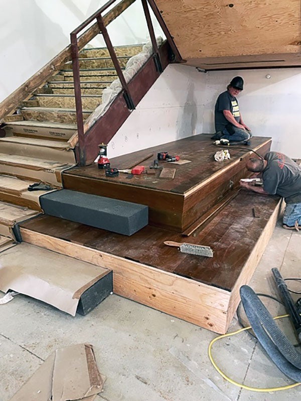 two people working on large platforms by some stairs